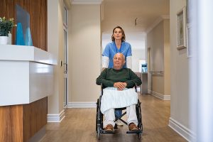 Nurse helping old man in wheelchair in nursing home. Healthcare