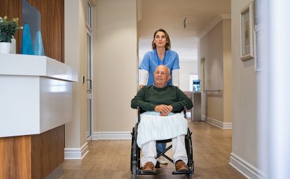 Nurse helping old man in wheelchair in nursing home. Healthcare